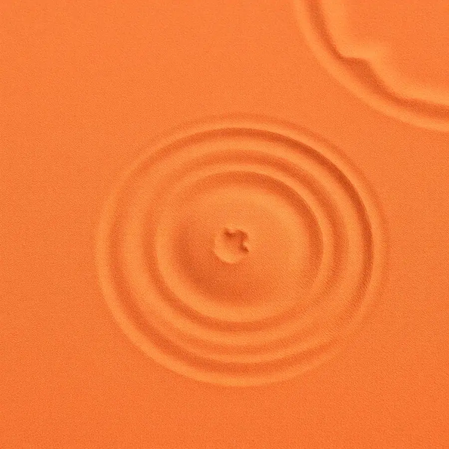 Concentric ripples pressed into warm clay-toned sand